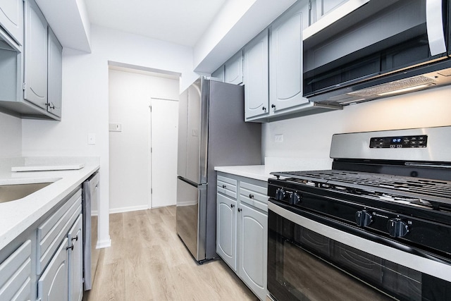 kitchen with appliances with stainless steel finishes, light countertops, light wood-style floors, and gray cabinetry