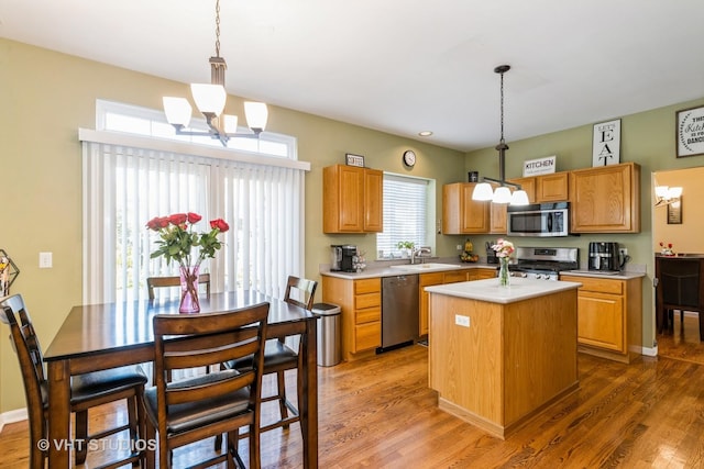 kitchen with wood finished floors, light countertops, appliances with stainless steel finishes, and a kitchen island