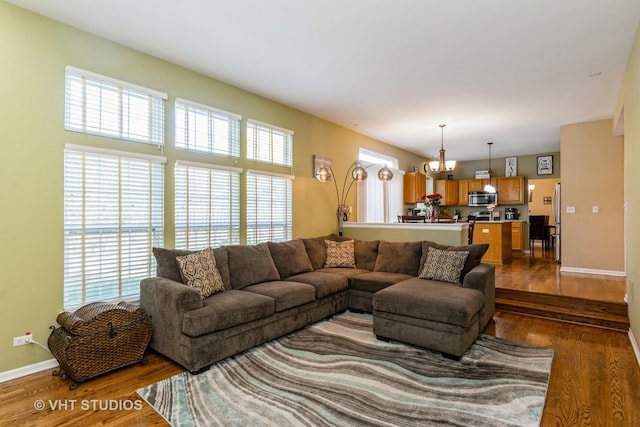 living area with a notable chandelier, baseboards, and wood finished floors