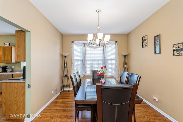 dining space with baseboards, a chandelier, and wood finished floors