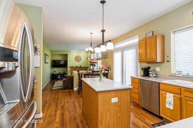 kitchen featuring appliances with stainless steel finishes, wood finished floors, a wealth of natural light, and a center island