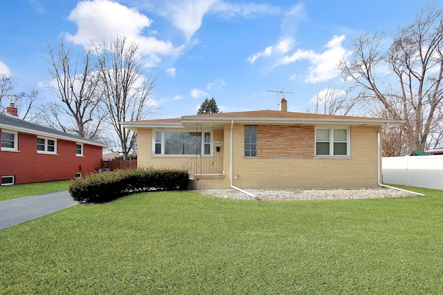 ranch-style home with brick siding, a chimney, a front yard, and fence