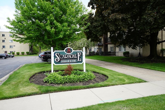 community / neighborhood sign featuring uncovered parking and a yard