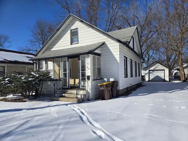 bungalow-style house with a garage, an outbuilding, and a sunroom