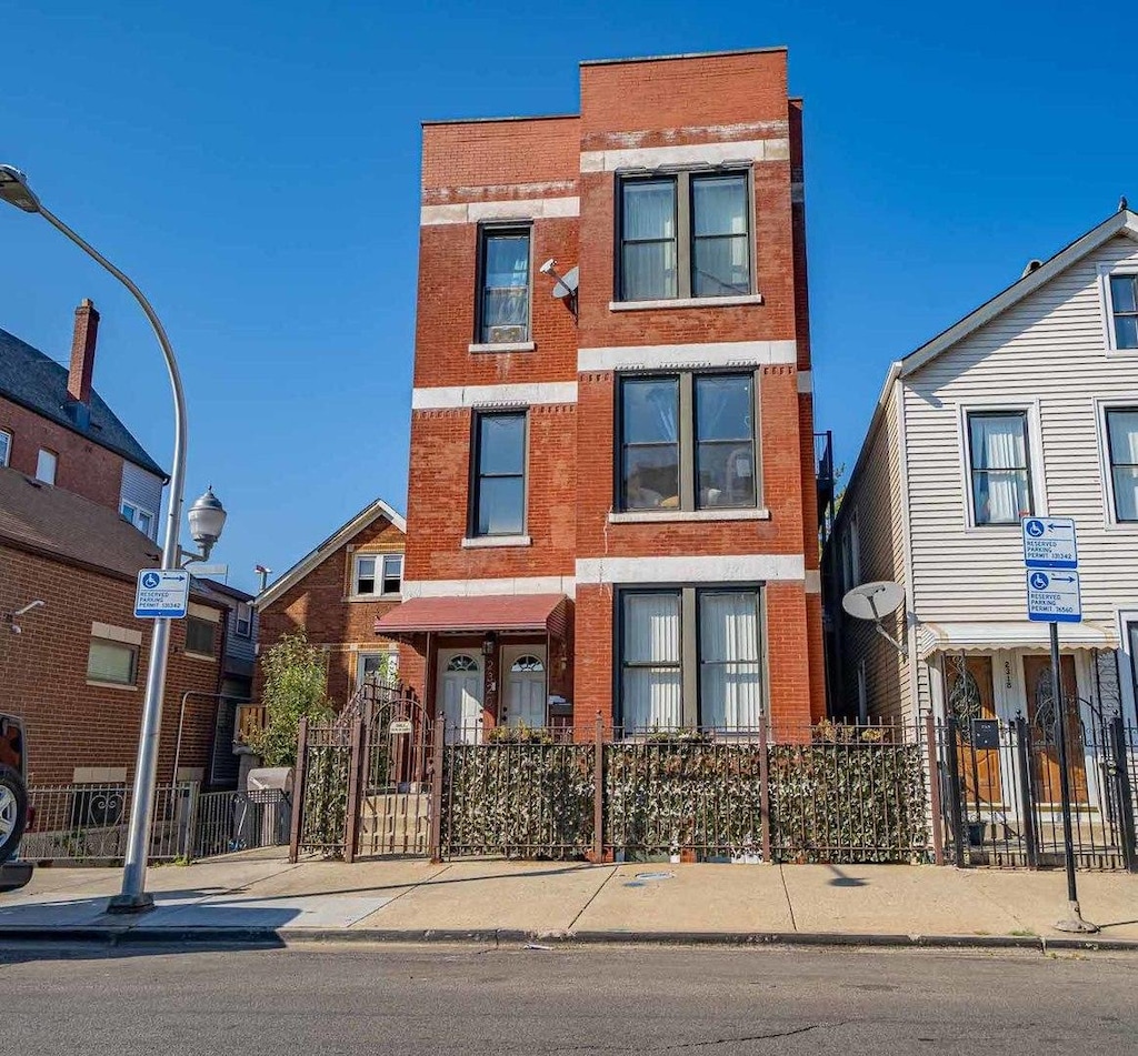 view of property featuring brick siding and a fenced front yard