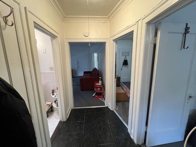 hallway with tile walls, attic access, and crown molding