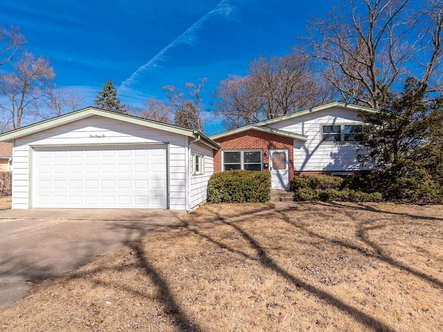 split level home with a garage, concrete driveway, and brick siding