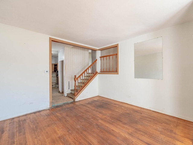 empty room featuring stairway and wood finished floors