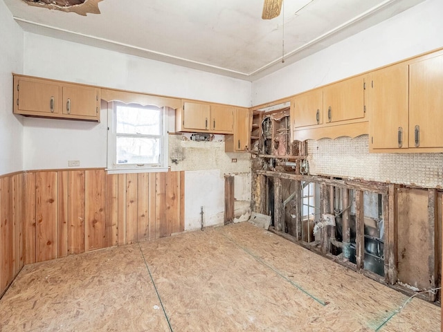 kitchen featuring a wainscoted wall, wood walls, and a ceiling fan