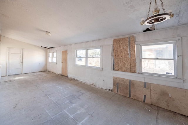 unfurnished room featuring vaulted ceiling and a textured ceiling