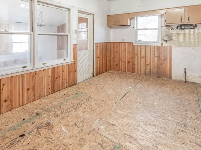 kitchen with a wainscoted wall, light countertops, and wood walls