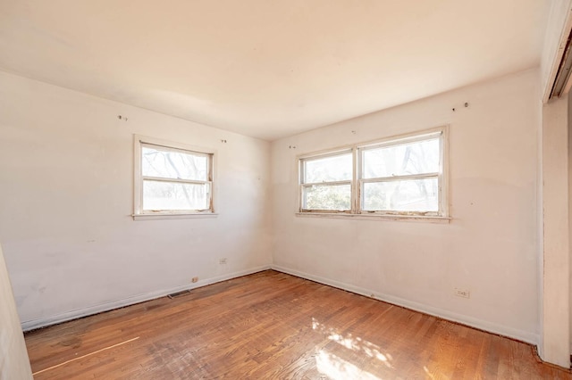 empty room featuring a wealth of natural light, baseboards, and wood finished floors