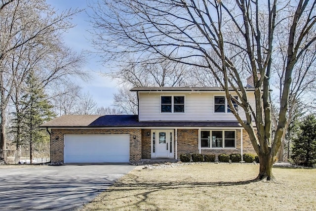 traditional-style home with aphalt driveway, an attached garage, and brick siding