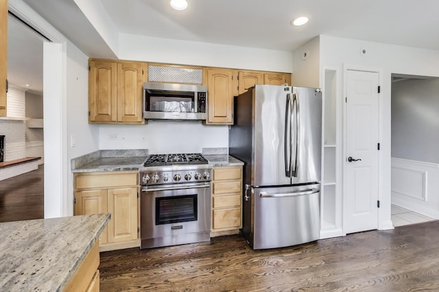 kitchen with dark wood finished floors, wainscoting, appliances with stainless steel finishes, and light brown cabinetry