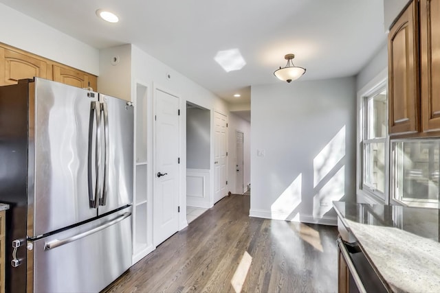 kitchen featuring light stone countertops, recessed lighting, freestanding refrigerator, brown cabinetry, and dark wood-style flooring