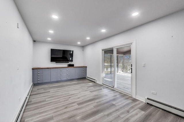 unfurnished living room featuring baseboard heating, recessed lighting, and light wood-style floors