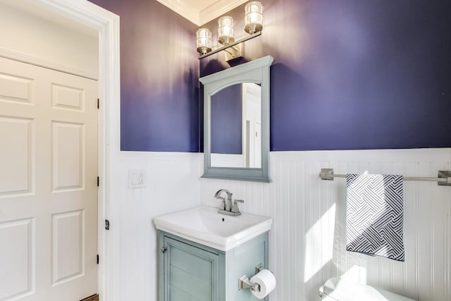 half bathroom featuring vanity and wainscoting