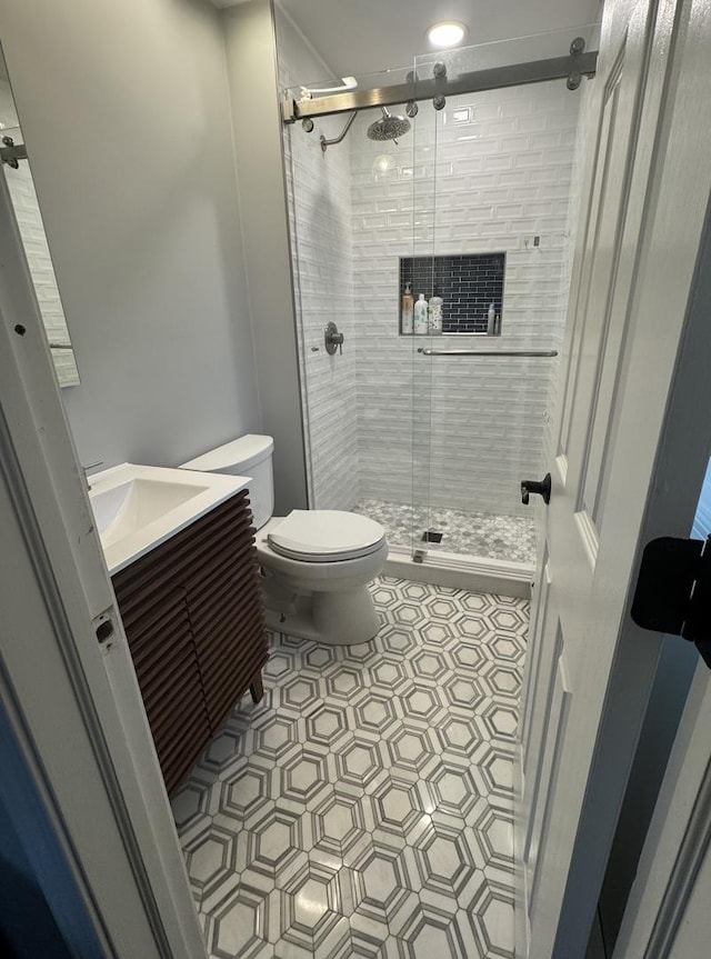 bathroom featuring tile patterned flooring, a shower stall, toilet, and vanity