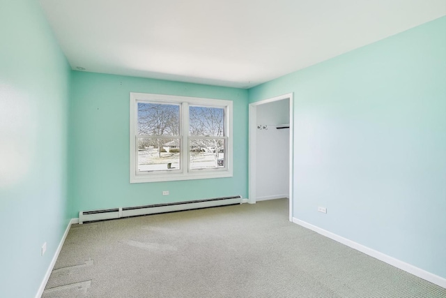 carpeted empty room with a baseboard heating unit and baseboards