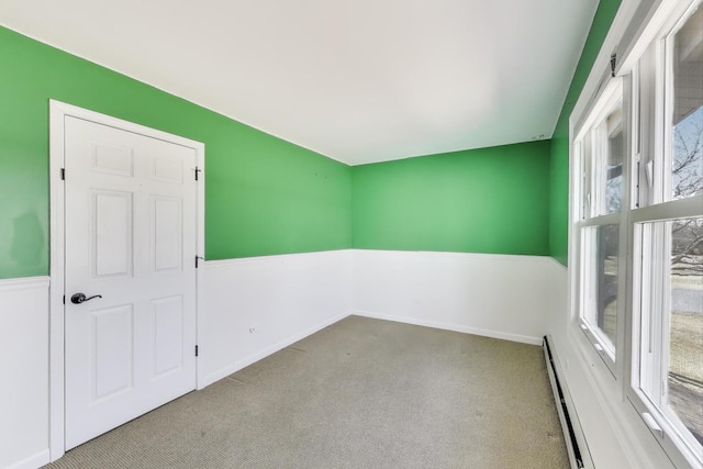 carpeted spare room featuring a baseboard heating unit, a baseboard radiator, and wainscoting