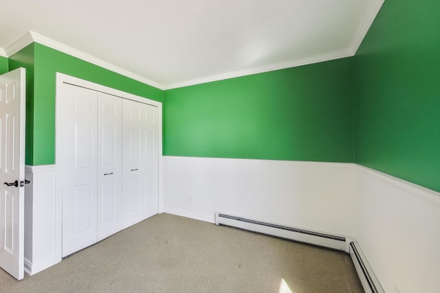 unfurnished bedroom featuring a baseboard heating unit, carpet, a closet, and crown molding