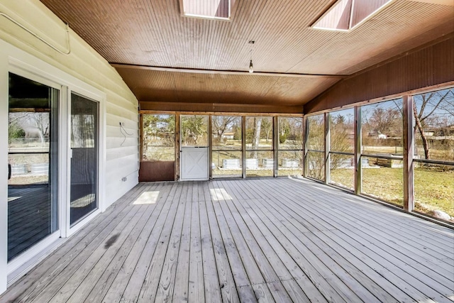 unfurnished sunroom with lofted ceiling with skylight, plenty of natural light, and wooden ceiling