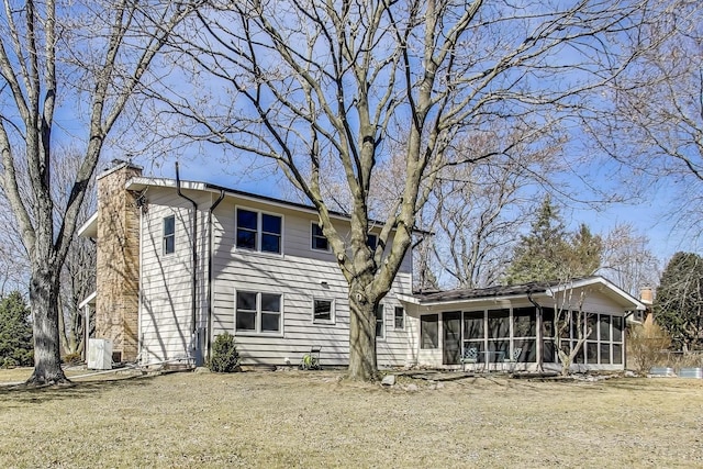 back of property featuring a chimney, a yard, and a sunroom