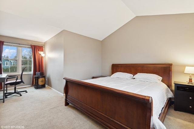 bedroom featuring lofted ceiling, baseboards, and light colored carpet