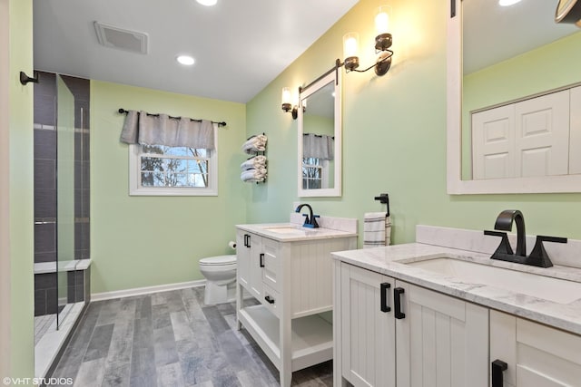 bathroom with two vanities, wood finished floors, visible vents, and a sink