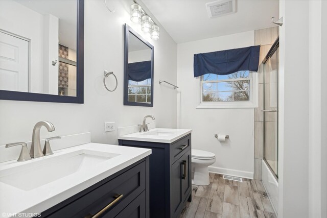 bathroom with two vanities, wood finished floors, visible vents, and a sink