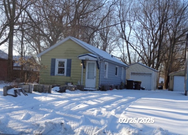 view of front of house with a detached garage and an outbuilding