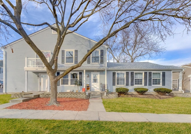 view of front of home with a balcony and a front lawn