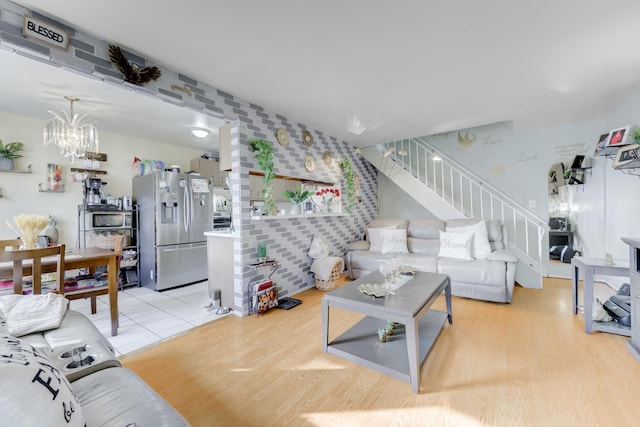 living area with wallpapered walls, stairway, light wood-type flooring, and an inviting chandelier