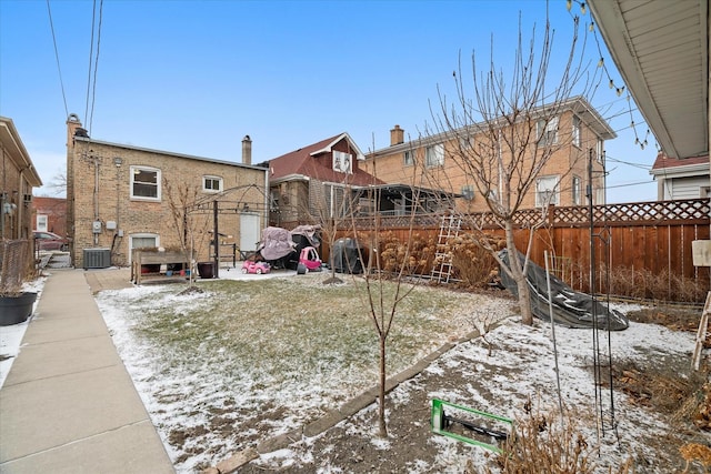 yard covered in snow with a fenced backyard and central air condition unit