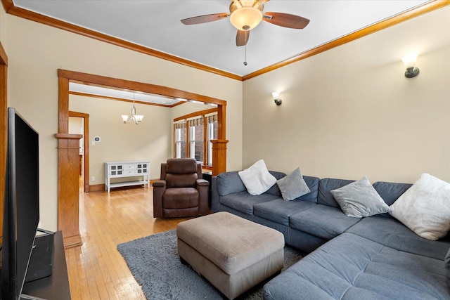 living area with light wood-type flooring, baseboards, ornamental molding, and ceiling fan with notable chandelier