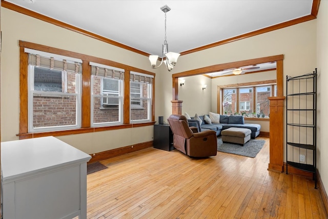 living area featuring a chandelier, baseboards, crown molding, and light wood finished floors