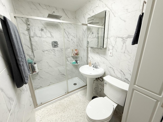 full bath with toilet, a sink, a marble finish shower, and tile walls