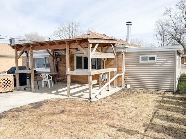 rear view of house featuring brick siding, a patio, and fence