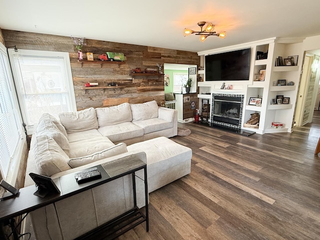 living room with a glass covered fireplace, wood walls, and wood finished floors