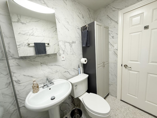 half bathroom with a sink, tile walls, and toilet