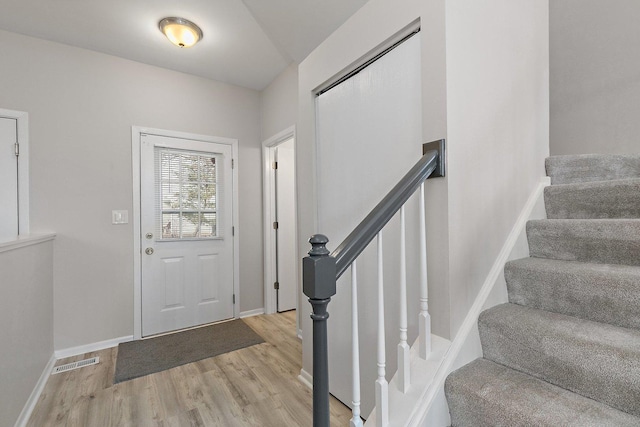 foyer with light wood-style flooring, stairway, visible vents, and baseboards