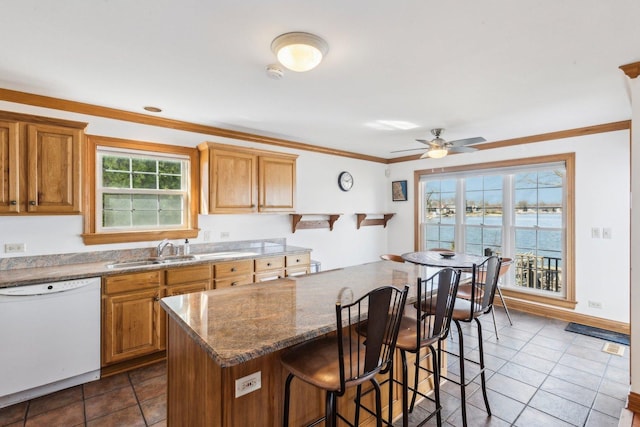 kitchen featuring a kitchen bar, ornamental molding, white dishwasher, a ceiling fan, and a sink