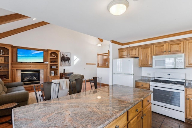 kitchen featuring dark tile patterned floors, open floor plan, dark stone counters, white appliances, and vaulted ceiling