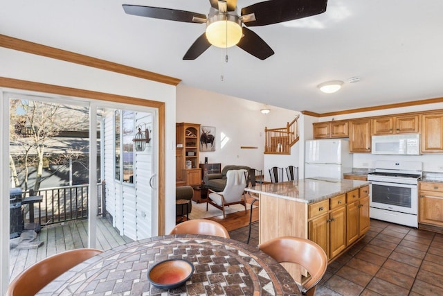 kitchen with white appliances, a ceiling fan, light stone countertops, a kitchen island, and a kitchen bar