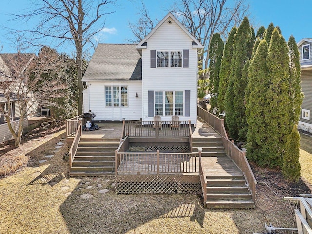 back of house featuring a wooden deck, roof with shingles, and stairs