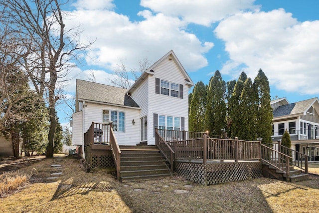 rear view of property with stairway, roof with shingles, and a deck