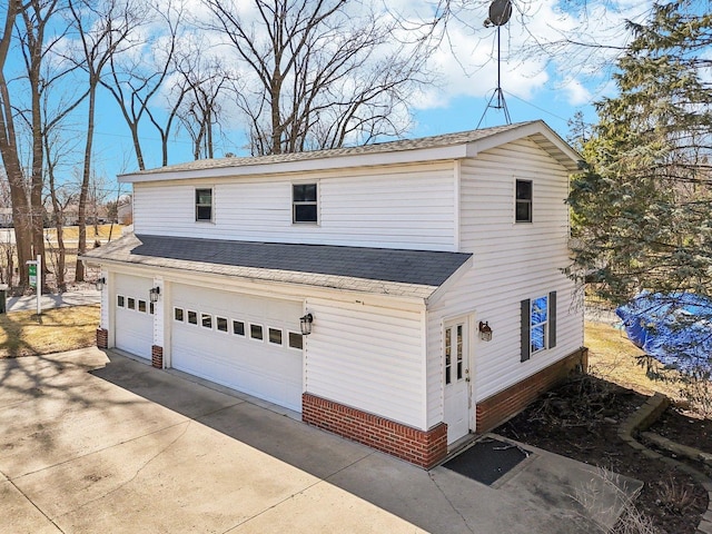 exterior space featuring concrete driveway, a garage, and a shingled roof