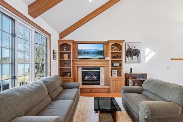 living area with lofted ceiling with beams, a water view, and a glass covered fireplace