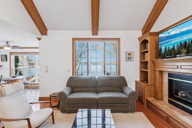 living area featuring a high end fireplace, beamed ceiling, ceiling fan, and wood finished floors