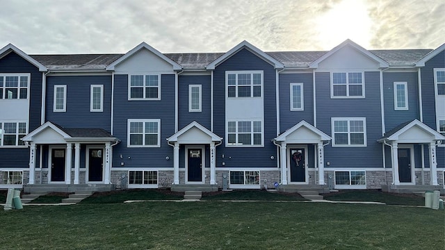 townhome / multi-family property featuring stone siding and a front lawn